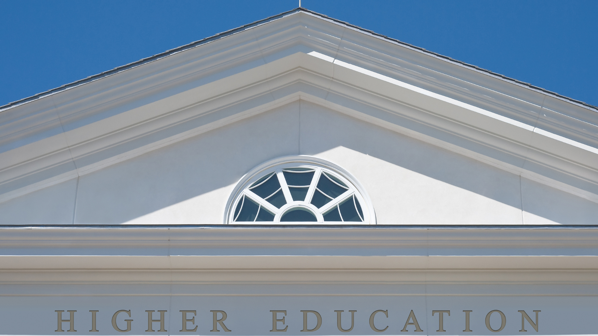 Greek-style architecture with the words "Higher Education" running across the bottom of an arch.