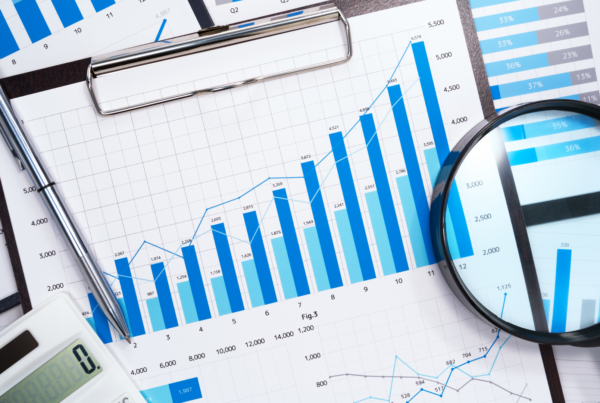 A magnifying glass hovers over a spread of charts and graphs.